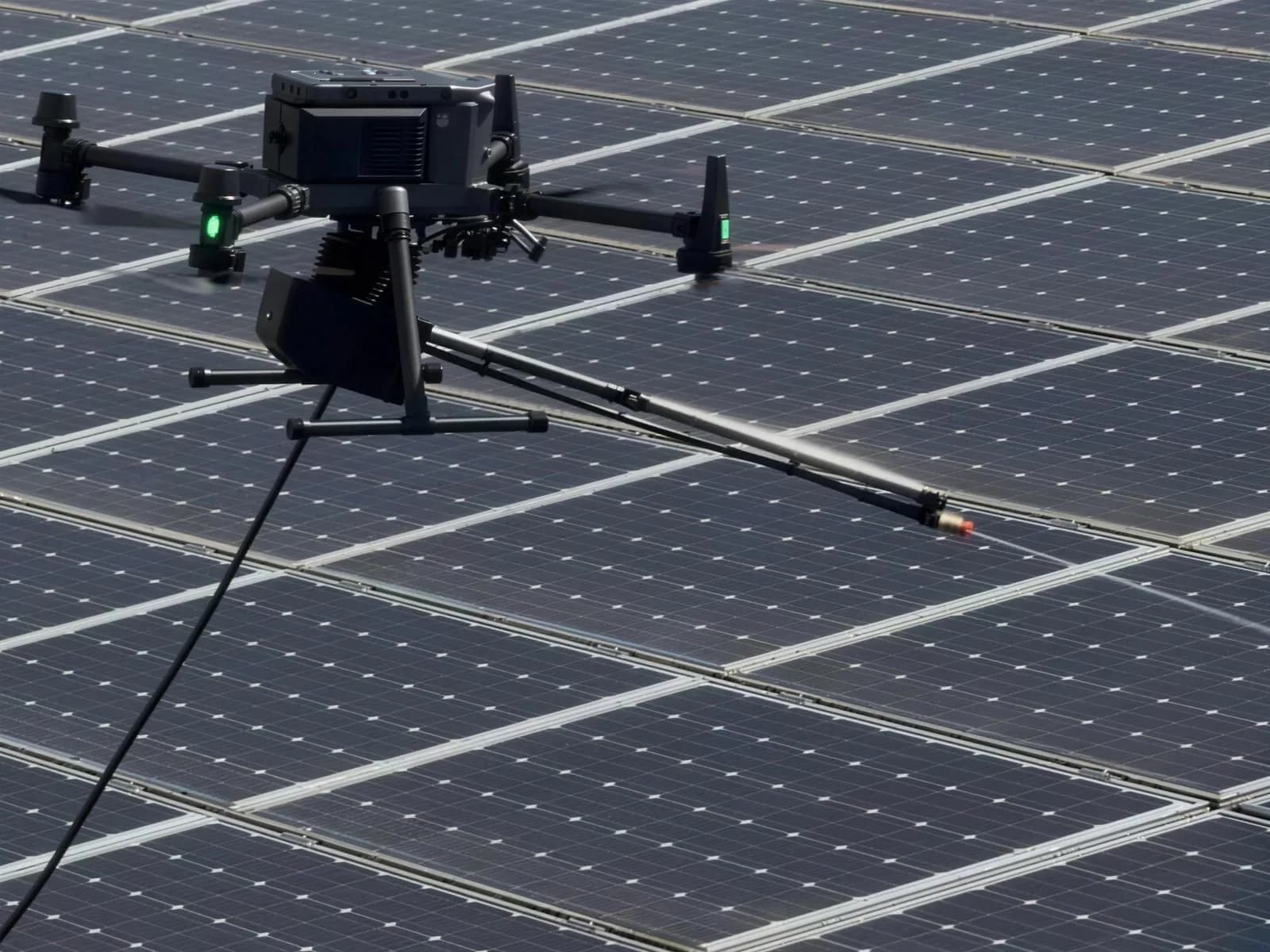 Il drone DJI Matrice 400 sopra i pannelli fotovoltaici, con la lancia di lavaggio e il tubo di alimentazione